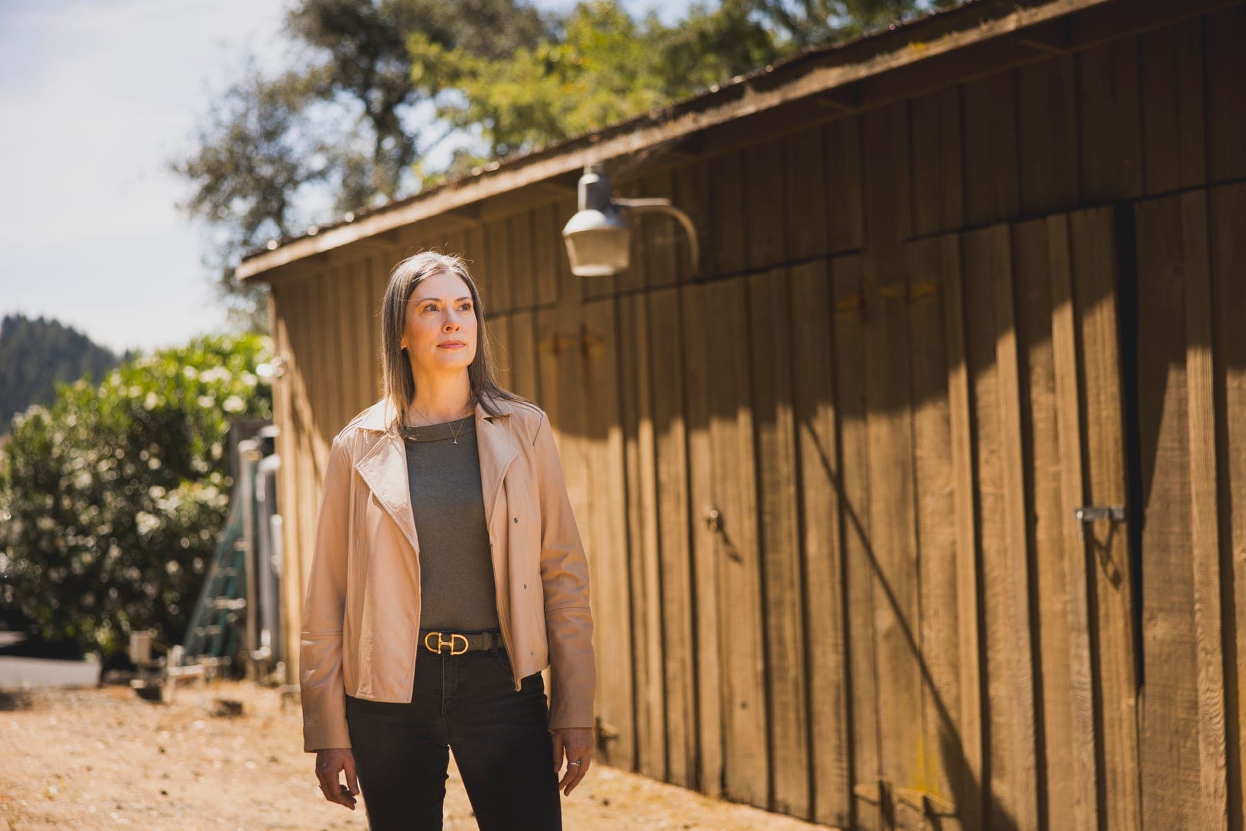 Kathleen Defever walking past a weathered wooden barn